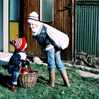 A woman helps a child with a basket outdoors.