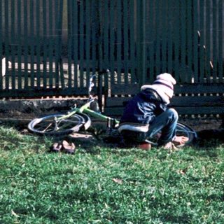 Person lying on grass beside fallen motorcycle.