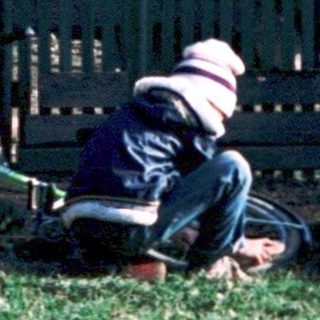 Person lying on grass beside fallen motorcycle.