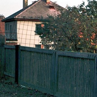 Child playing outside near wooden fence.