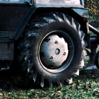 Two workers harvesting fruit with tractor-assisted equipment.