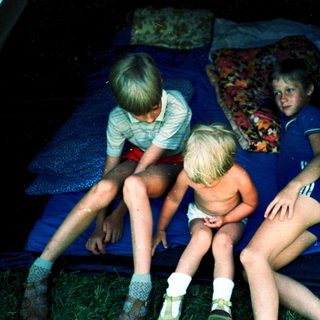 Three children sitting together in dark water.