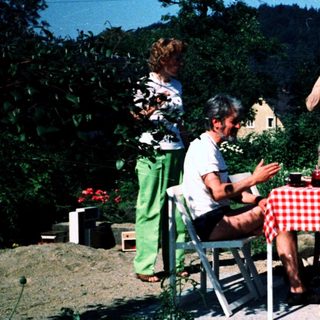 Family picnic outdoors in garden setting.