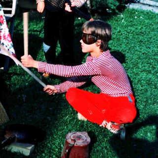 Two children playing with brooms outdoors.