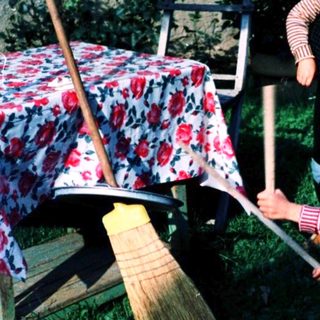 Two children playing with brooms outdoors.