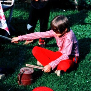 Two children playing outside with gardening tools.