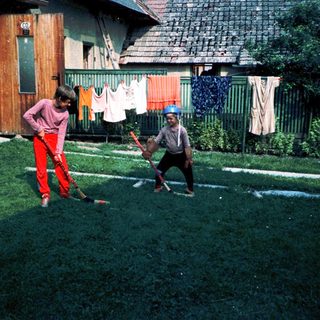 Two children playing with baseball bats outdoors.
