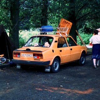Family camping setup with car, tents, and outdoor gear.