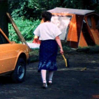 Family camping setup with car, tents, and outdoor gear.