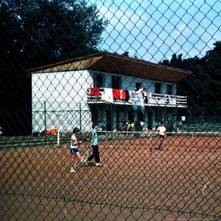 Children playing tennis on outdoor court.