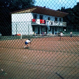 Children playing soccer on a fenced field.