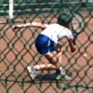 Children playing soccer on a fenced field.
