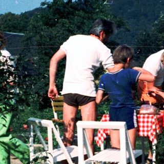 Group of people sitting on bleachers outdoors in a garden.