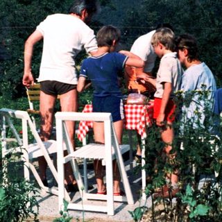 Group of people sitting on bleachers outdoors in a garden.