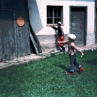 Two children playing with a frisbee near a building.