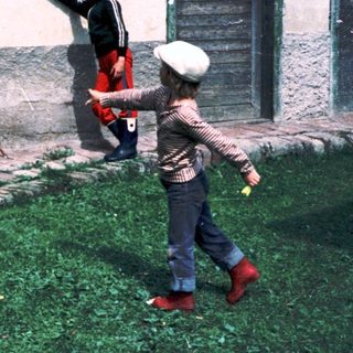 Two children playing with a frisbee near a building.