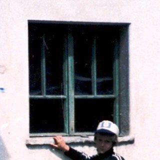 Two children playing with a frisbee near a building.