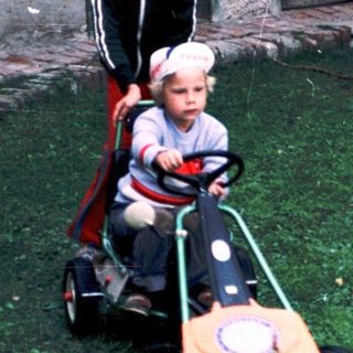 Two children playing with toy cars in courtyard.