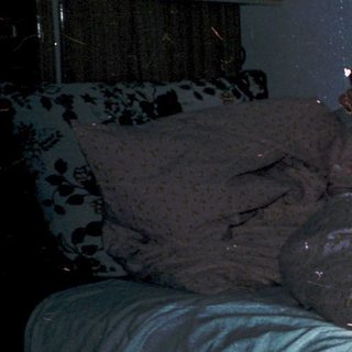 Child lying in bed reading under dim light.