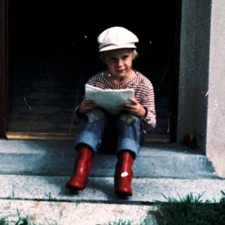 Child reading book outdoors on steps.