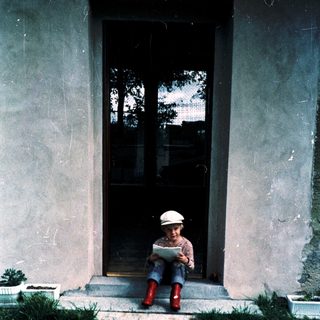 Child reading book outdoors on steps.