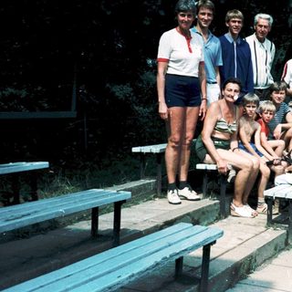 Family group posing outdoors at stadium seating area.