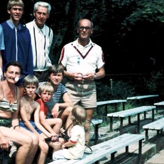 Family group posing outdoors at stadium seating area.