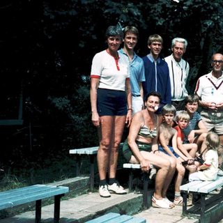 Family group posing outdoors at stadium seating area.