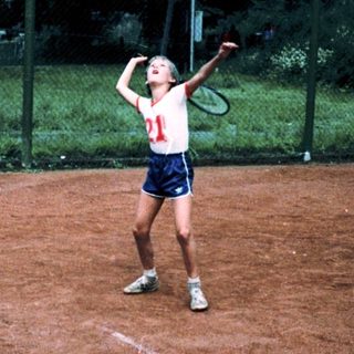 Person playing tennis on clay court.