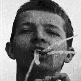 Young man smoking cigarette while drinking coffee.