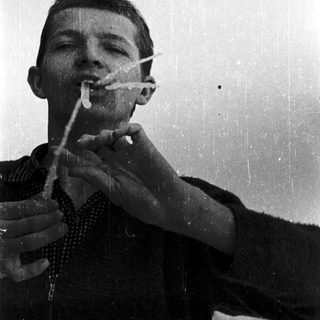 Young man smoking cigarette while drinking coffee.