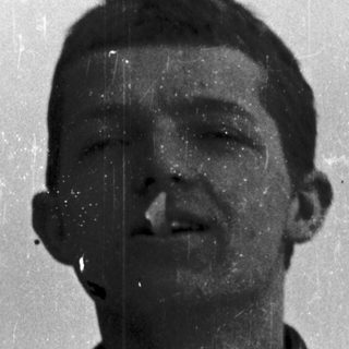 Young man smiling in vintage-style photograph.