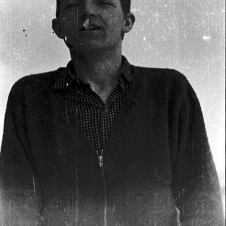 Young man smiling in vintage-style photograph.