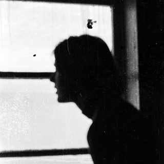 Silhouette of person looking out window.