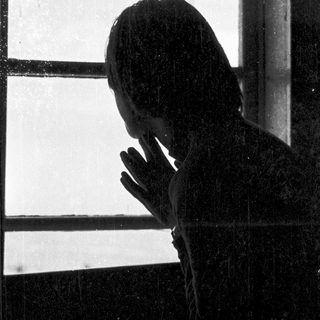 Silhouette of person leaning on window.