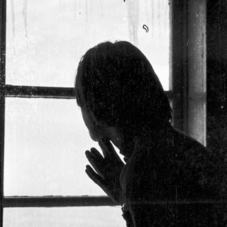 Silhouette of person leaning on window.