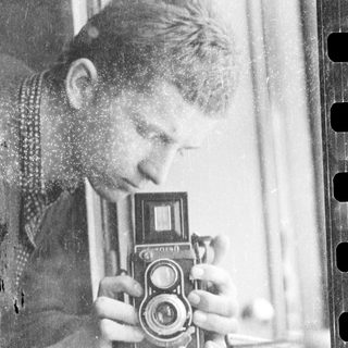 Person using vintage twin-lens reflex camera indoors.