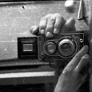 A person taking a self-portrait with a vintage twin-lens reflex camera.