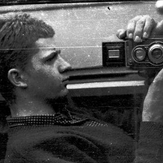 A person taking a self-portrait with a vintage twin-lens reflex camera.