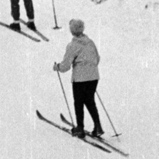 People skiing on snow-covered forest path.