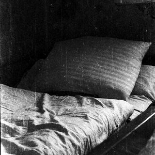 Unmade bed with rumpled sheets and pillows.