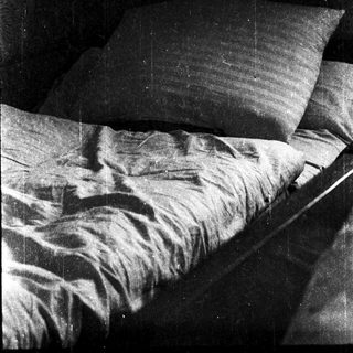 Unmade bed with rumpled sheets and pillows.