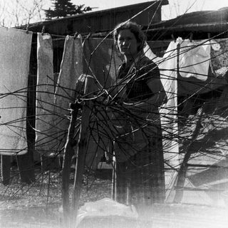 Woman cutting barbed wire in rural setting.