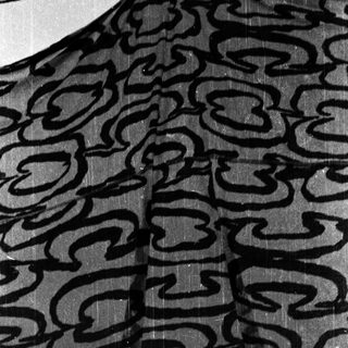 Black patterned umbrella with cloud-like designs, open in rain.