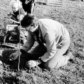 Man planting tree with child observing nearby.