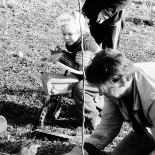 Man planting tree with child observing nearby.