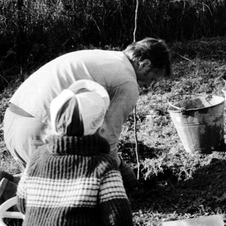 Two people fishing with a reel and bucket.