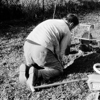 Two people operating portable water well drilling equipment.