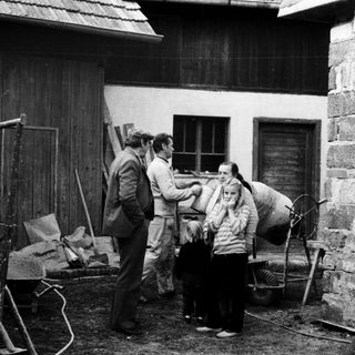 People gathered around a woman in a courtyard.