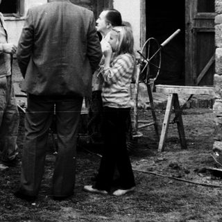 People discussing near a rustic building with construction tools.